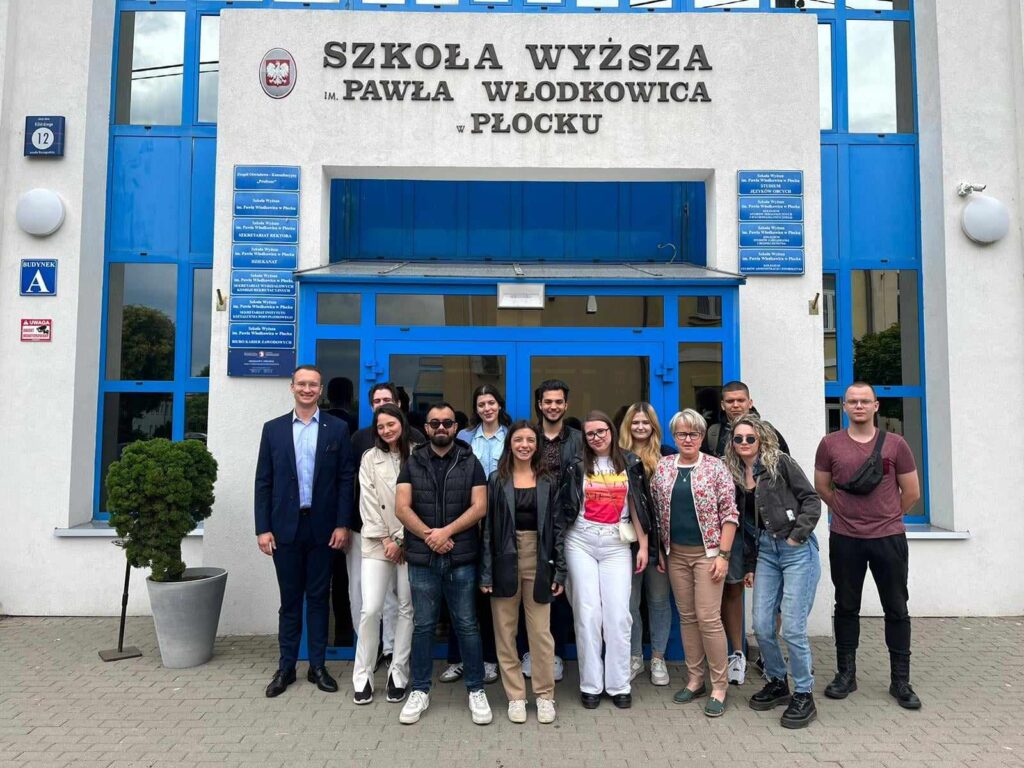 Grupa osób stojących przed wejście do budynku