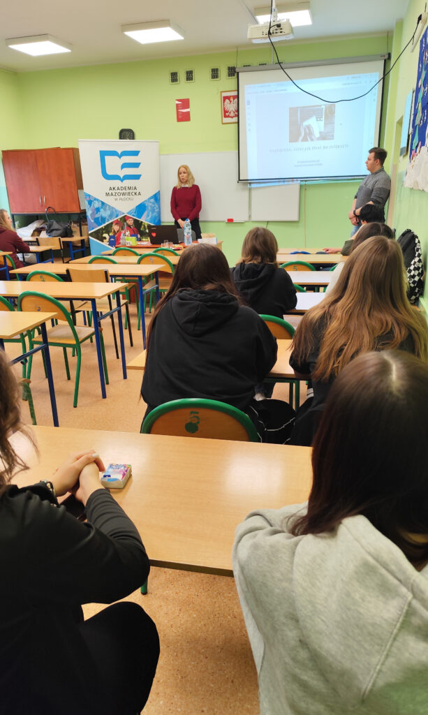 Nauczycielka akademicka omawiająca prezentację z podstaw webwritingu przed uczniami siedzącymi w ławkach szkolnych