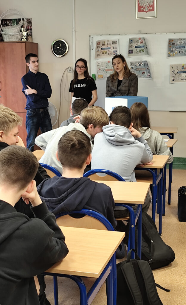 Nauczycielka akademicka omawiająca prezentację z podstaw ekonomii przed uczniami siedzącymi w ławkach szkolnych