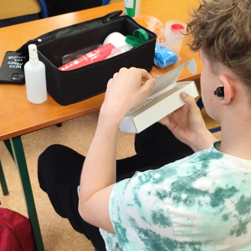 Student oglądający pudełko ze sprzętem kryminalistycznym podczas warsztatów kryminalistycznych