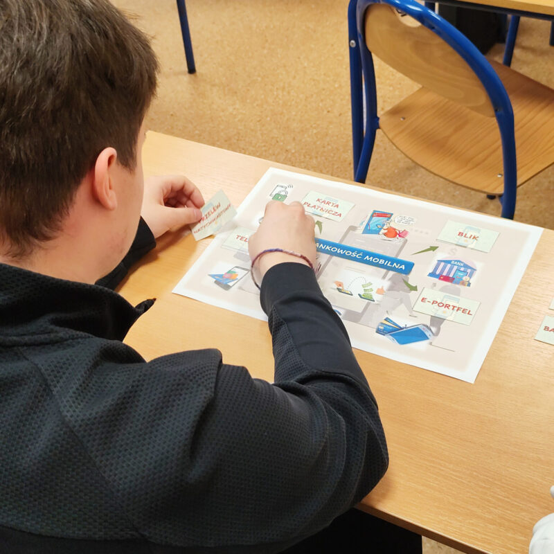Student rozwiązujący zagadkę ekonomiczną podczas warsztatów z podstaw ekonomii.