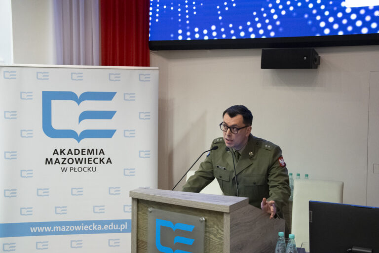 Zdjęcie prowadzącego wykład prelegenta sympozjum przy mównicy