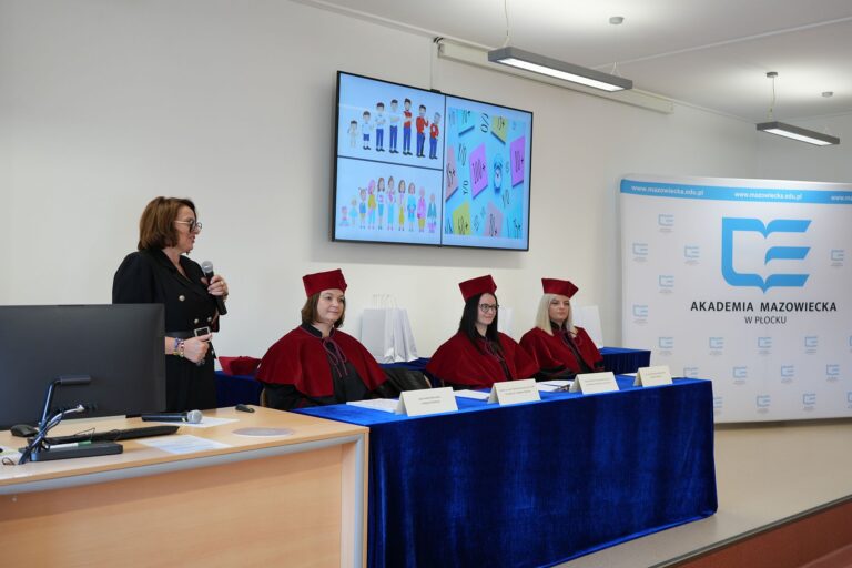 Realizatorzy projektu ze strony AMP w strojach akademickich, siedzący za stołem prezydialnym,