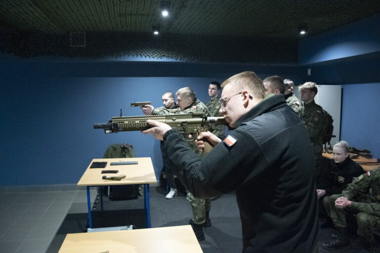 Licealiści mierzący do celu z laserowych karabinów na wirtualnej strzelnicy