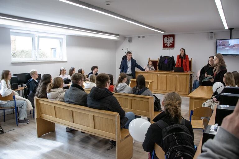 Licealiści siedzący w ławach sali prawniczej podczas dyskusji