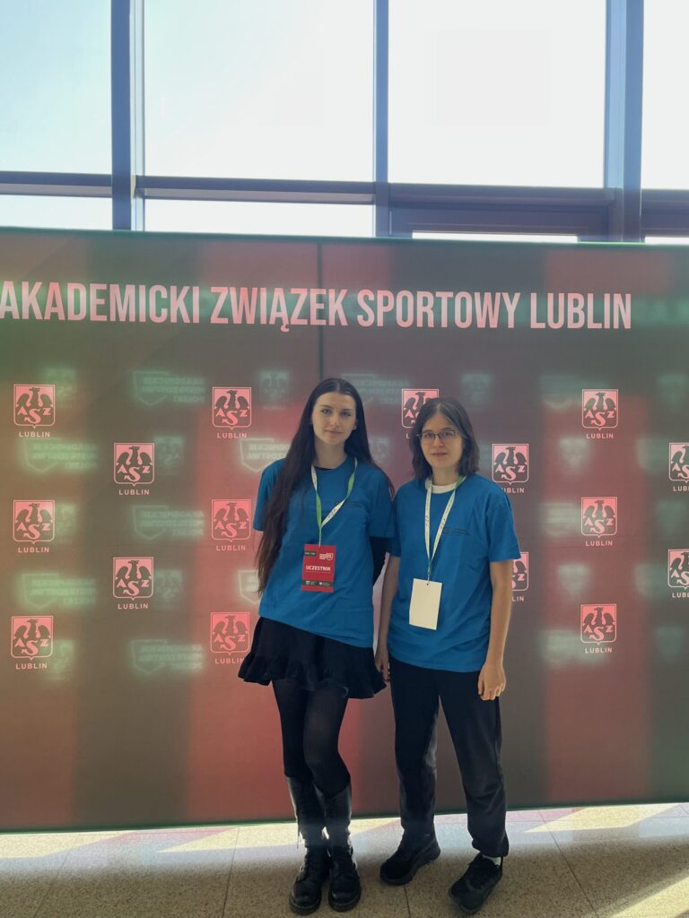 Studentki AMP na tle ścianki promocyjnej, pozujące do zdjęcia