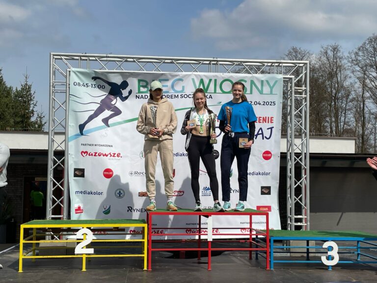 Laureatki 3 pierwszych miejsc w Biegu wiosny stoją razem na najwyższym stopniu podium, za nimi ścianka