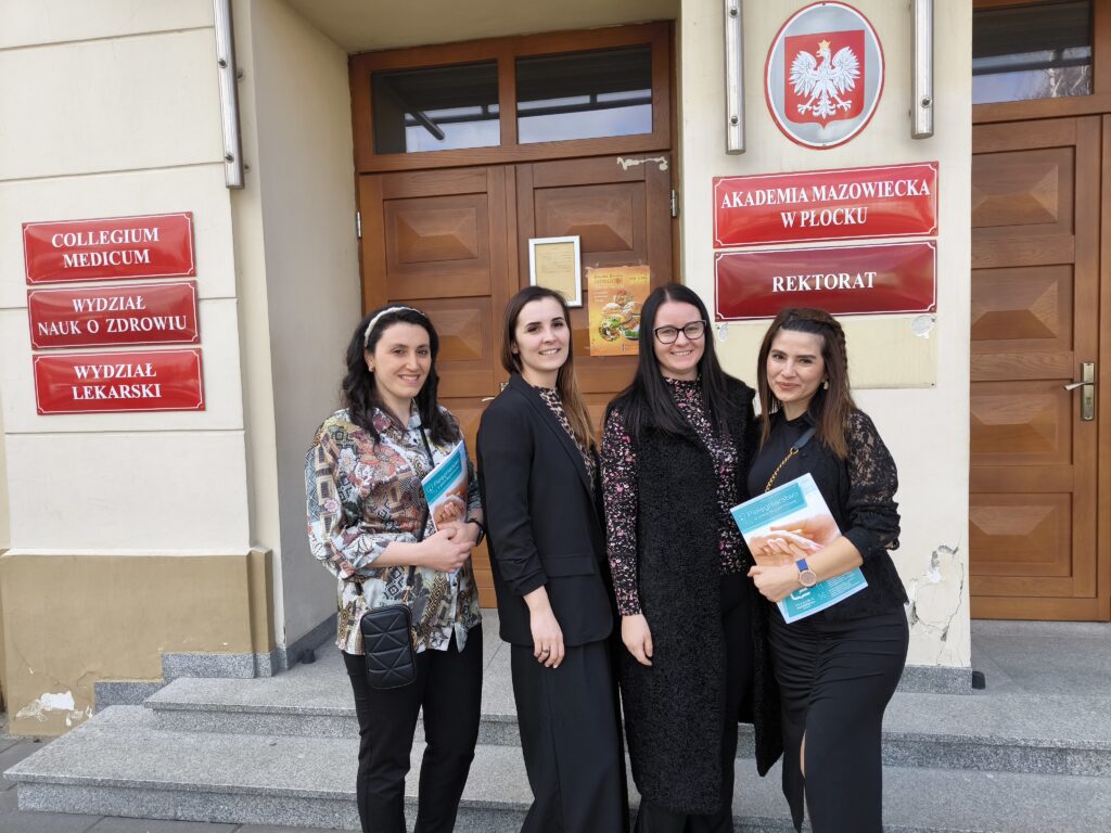 nauczyciele akademiccy i przedstawiciele zagranicznej uczelni pozują do zdjęcia na tle wejścia do AMP