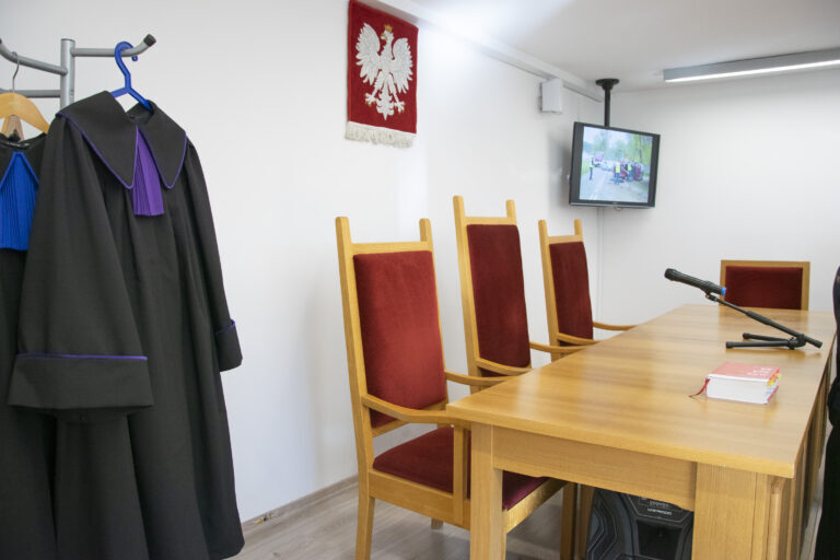 Widok na katedrę sali sądowej z togami sądowniczymi oraz ławami