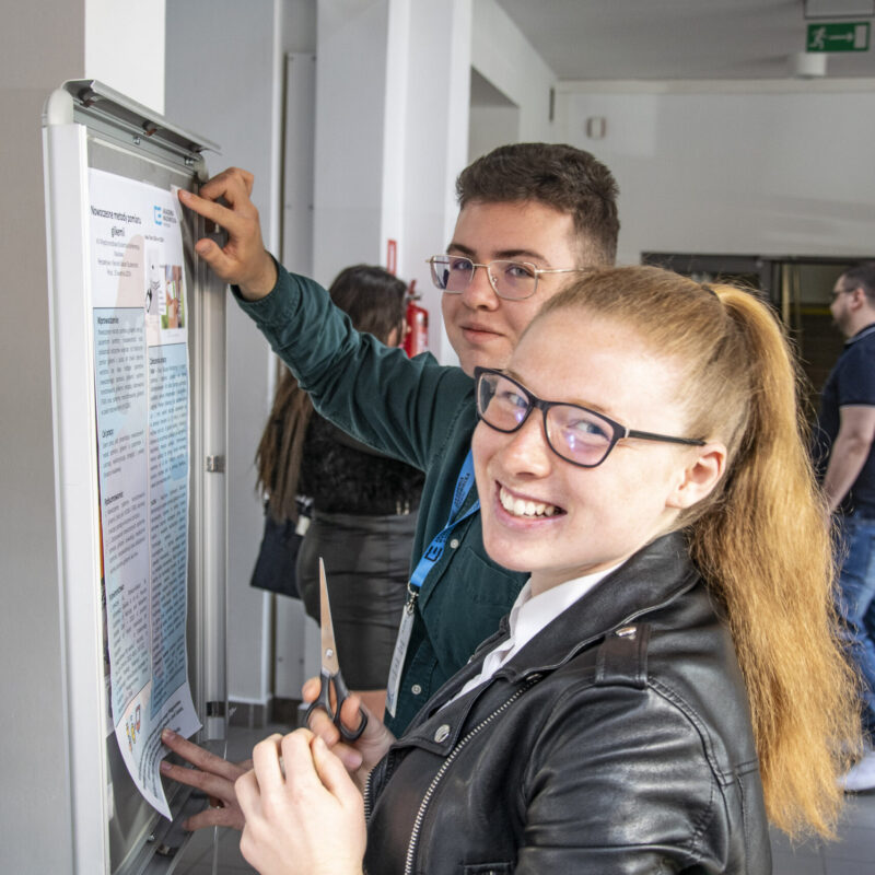 Pozowane zdjęcie dwójki studentów podczas przymocowywania plakaty do ramki