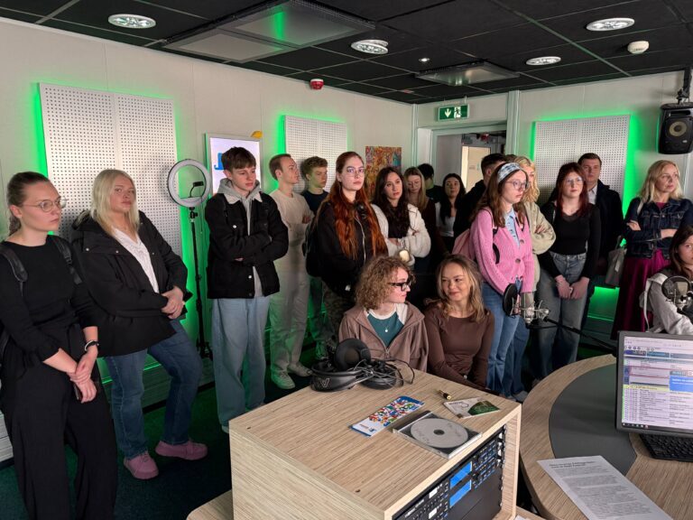 Studenci stojący i siedzący w studiu nagraniowym, podczas wycieczki w Polskim Radiu