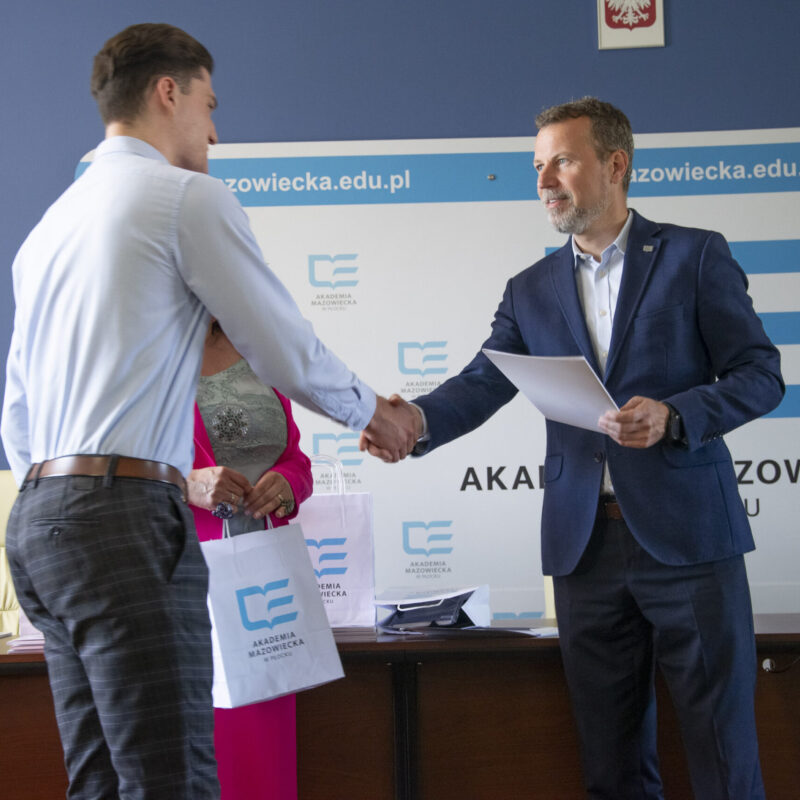 Rektor wręczający dyplom studentowi w towarzystwie Pani prorektor