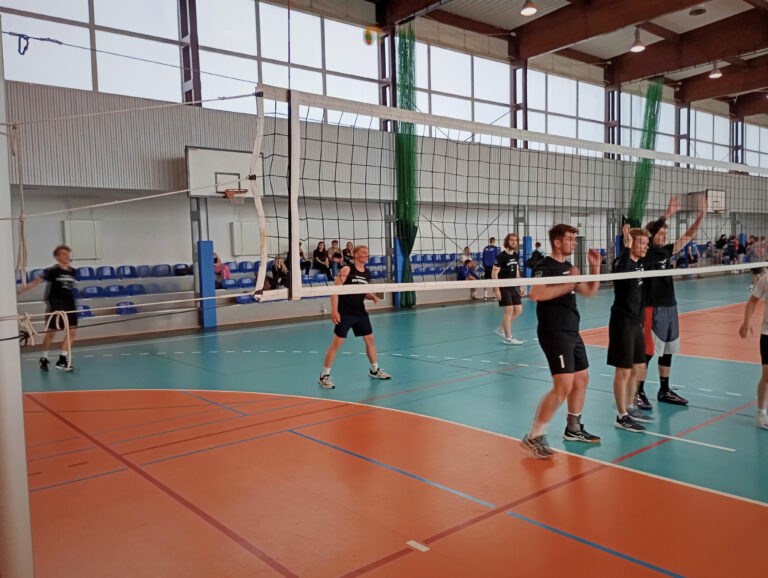 Mężczyźni na boisku hali sportowej rozgrywający mecz piłki siatkowej